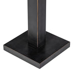 Detail of the dark square base and rectangular stem, with fine warm-toned edging along the corners.