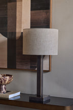 Rectangular stem table lamp on a dark console beneath abstract artwork, beside stacked books and a marbled decorative bowl.