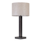 Angled view of the table lamp on white, showing two faces of the bronze stem, square base and pale fabric drum shade.