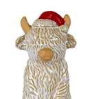 Close-up of the cow figure's rounded tan muzzle, raised cream shaggy coat, side ears and tan horns framing a glossy red hat with pale textured trim.