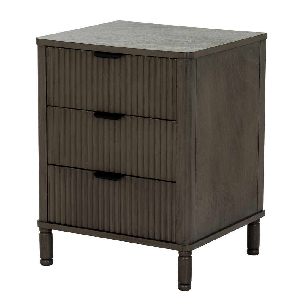Angled view of the dark grey-brown bedside table showing three reeded drawer fronts, dark cup pulls, a plain side panel and short shaped feet.