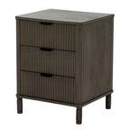 Angled view of the dark grey-brown bedside table showing three reeded drawer fronts, dark cup pulls, a plain side panel and short shaped feet.