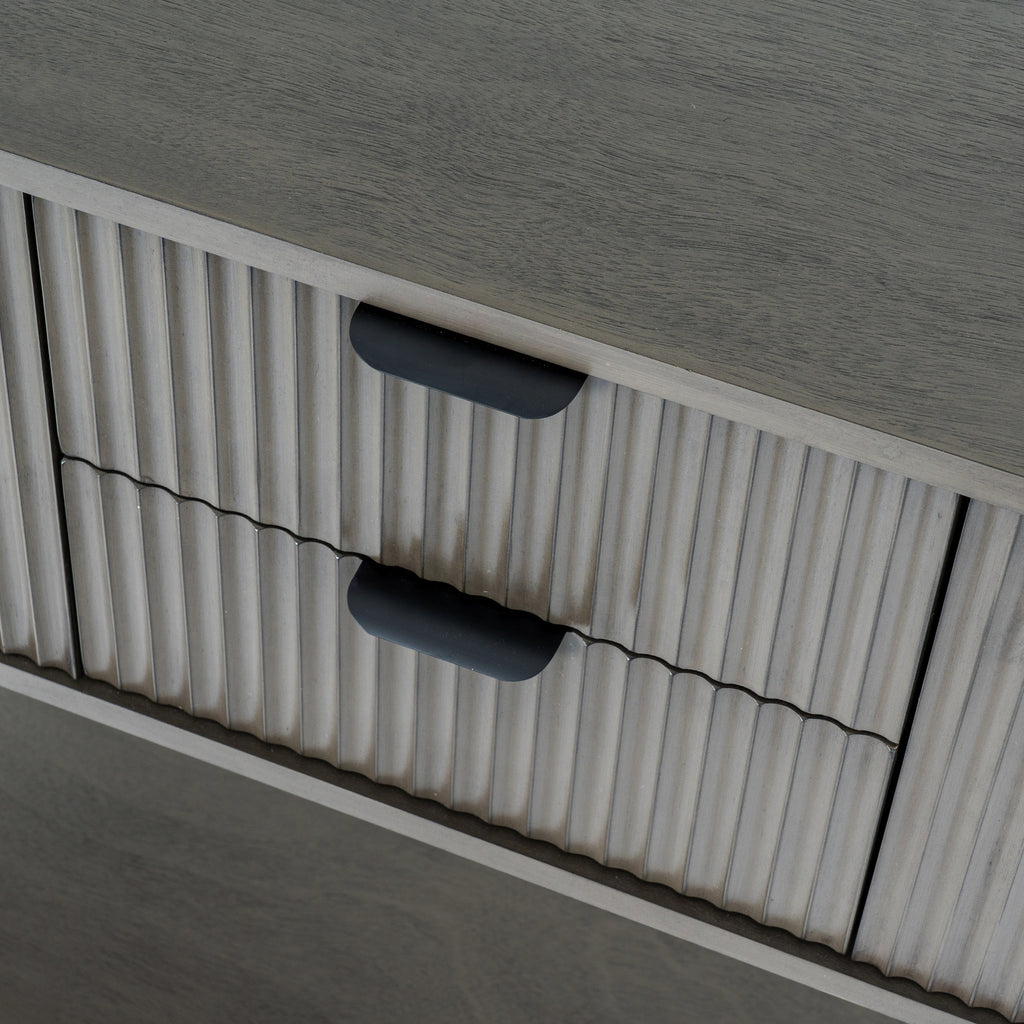 Close-up of the console's two vertically reeded drawer fronts and dark cup-shaped pulls beneath the grain-textured top.