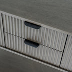 Close-up of the console's two vertically reeded drawer fronts and dark cup-shaped pulls beneath the grain-textured top.