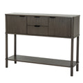 Angled view of a dark grey-brown console table with two reeded cupboard doors, two central drawers, dark cup-shaped pulls and a full-width lower shelf.