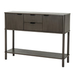 Angled view of a dark grey-brown console table with two reeded cupboard doors, two central drawers, dark cup-shaped pulls and a full-width lower shelf.