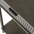 Close-up from above showing the console's grain-textured top, a dark cup-shaped pull and vertical reeding, with part of a leg and lower shelf below.