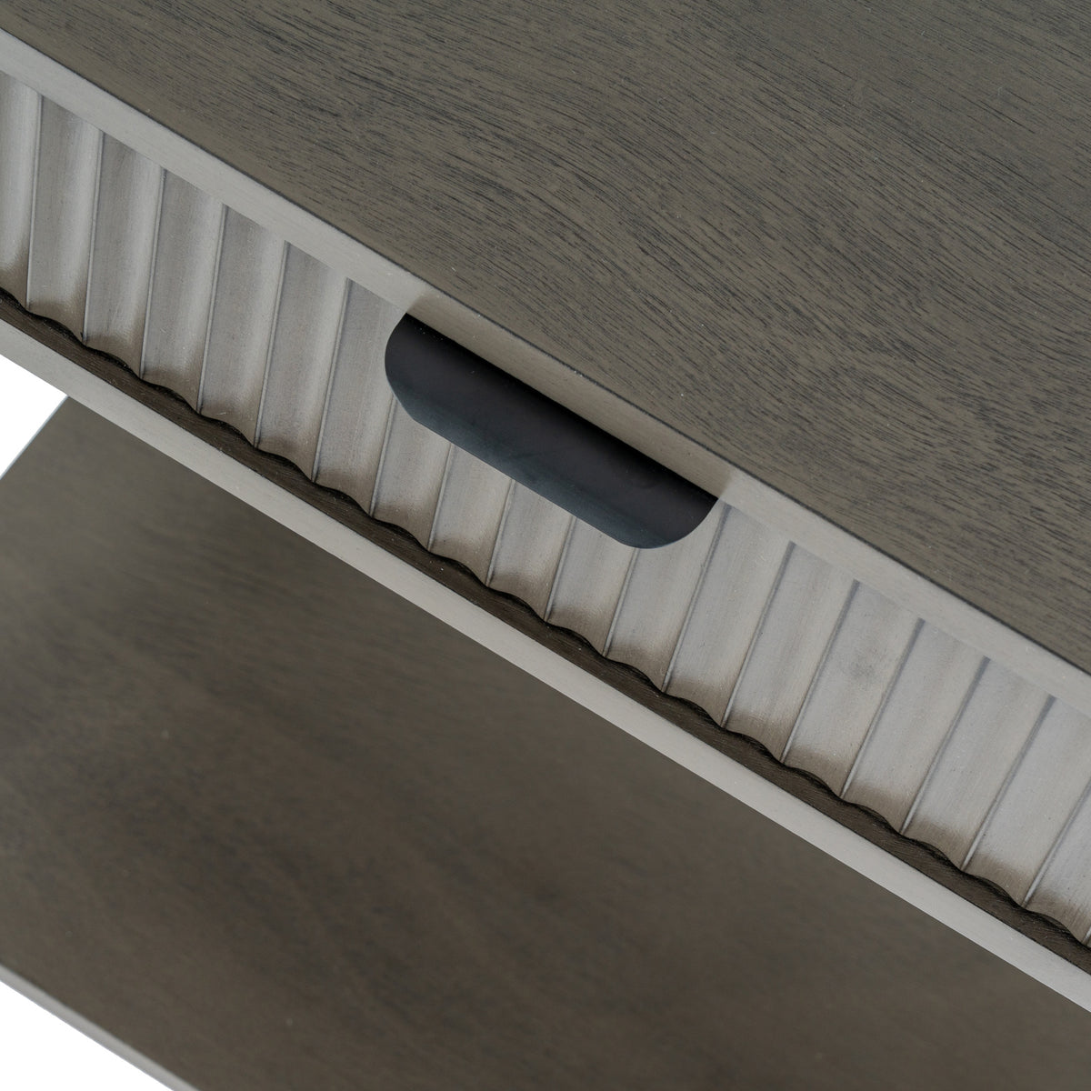 Angled close-up of the dark cup-shaped drawer pull beneath the grained top, with rounded vertical reeds across the drawer front.