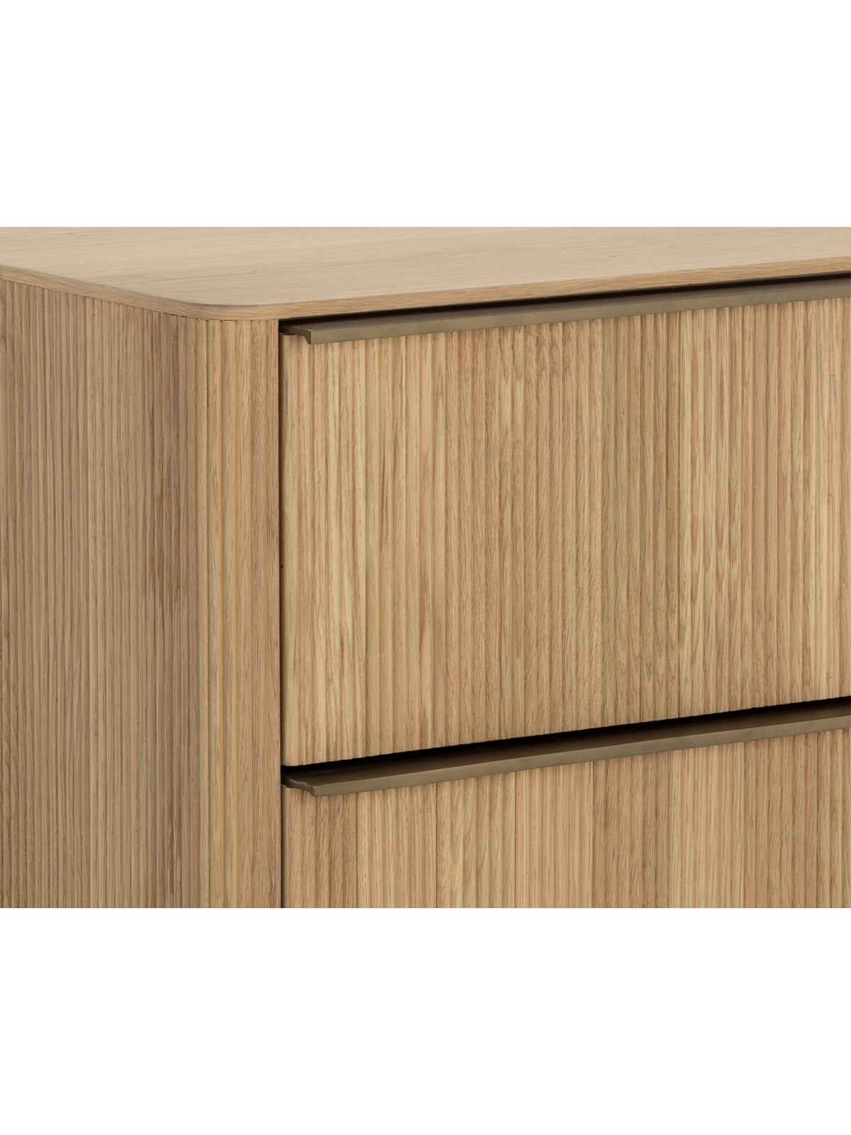 Close-up of the nightstand's rounded upper corner, wood grain, reeded drawer fronts and horizontal metal pulls.