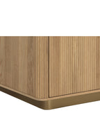 Detail of the nightstand's reeded wood panels and rounded lower corner above the gold-toned base.