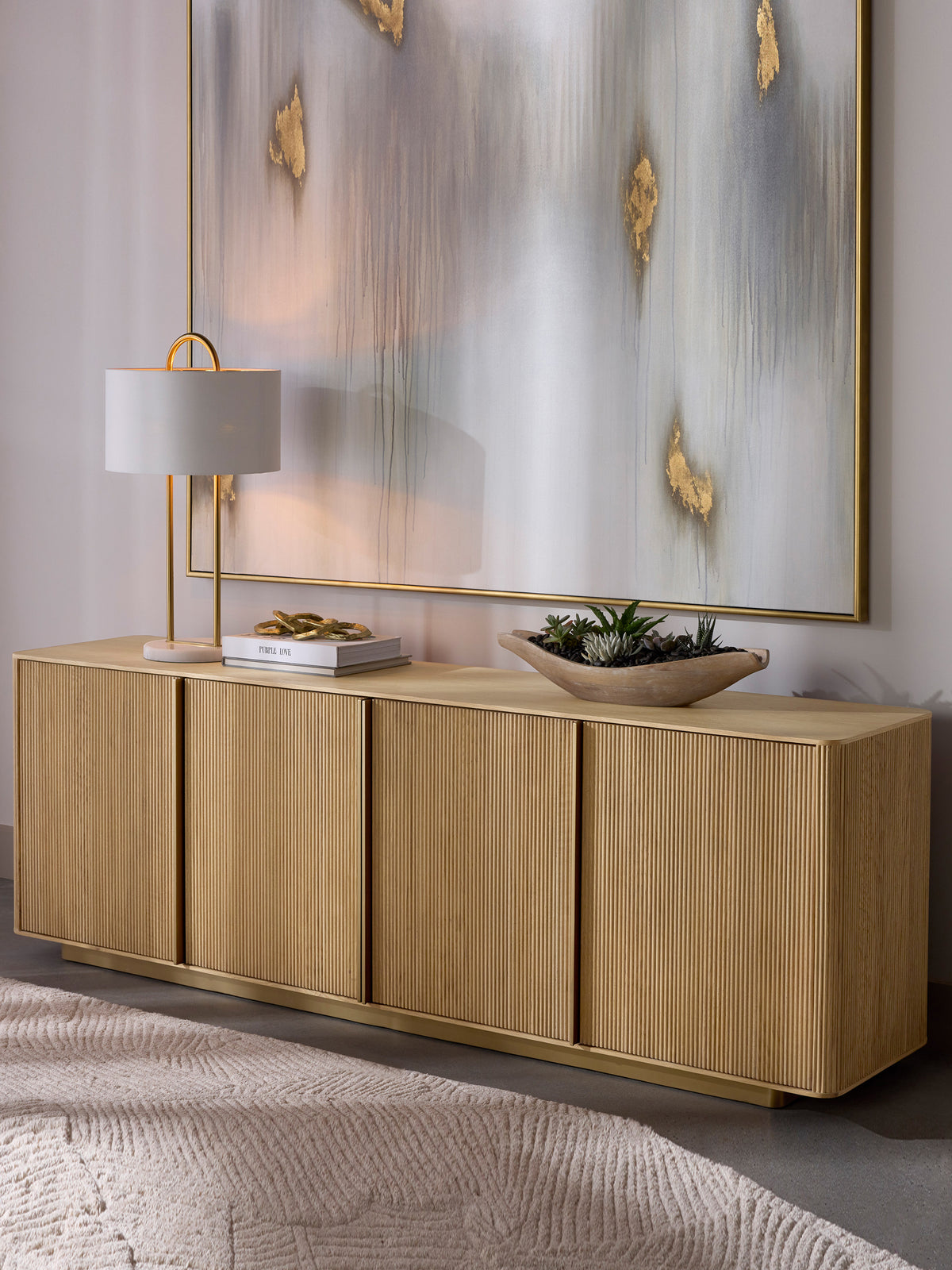 Reedline Sideboard styled beneath a large abstract artwork, with a table lamp, books and a shallow bowl of succulents on top.
