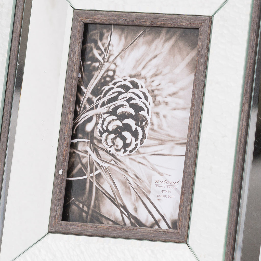 Close-up of the pine-cone picture insert and wood-grain-effect brown aperture border, with reflective panels and diagonal corner joins visible around it.