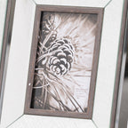 Close-up of the pine-cone picture insert and wood-grain-effect brown aperture border, with reflective panels and diagonal corner joins visible around it.