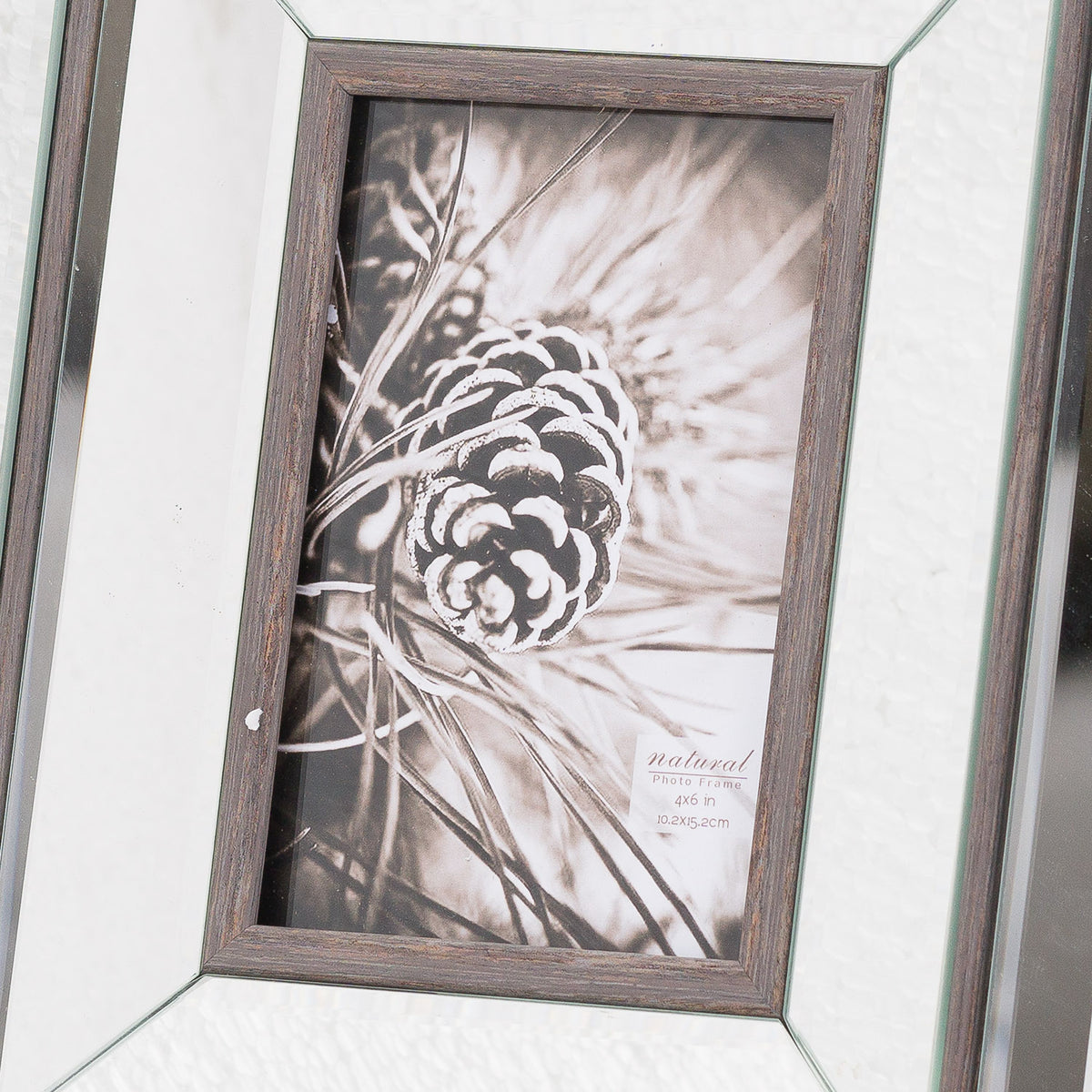 Close-up of the pine-cone picture insert and wood-grain-effect brown aperture border, with reflective panels and diagonal corner joins visible around it.