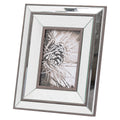 Angled view of a portrait photo frame with a stepped reflective surround, dark brown borders and a black-and-white pine cone picture.