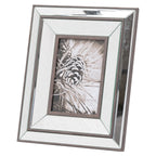 Angled view of a portrait photo frame with a stepped reflective surround, dark brown borders and a black-and-white pine cone picture.