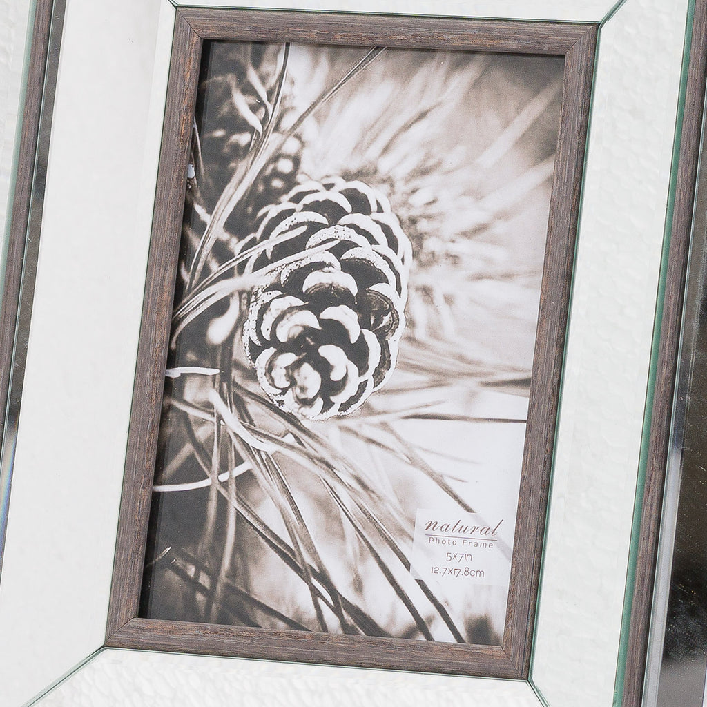 Close-up of the frame's brown grain-effect inner border and bright reflective panels around a black-and-white pine cone picture.