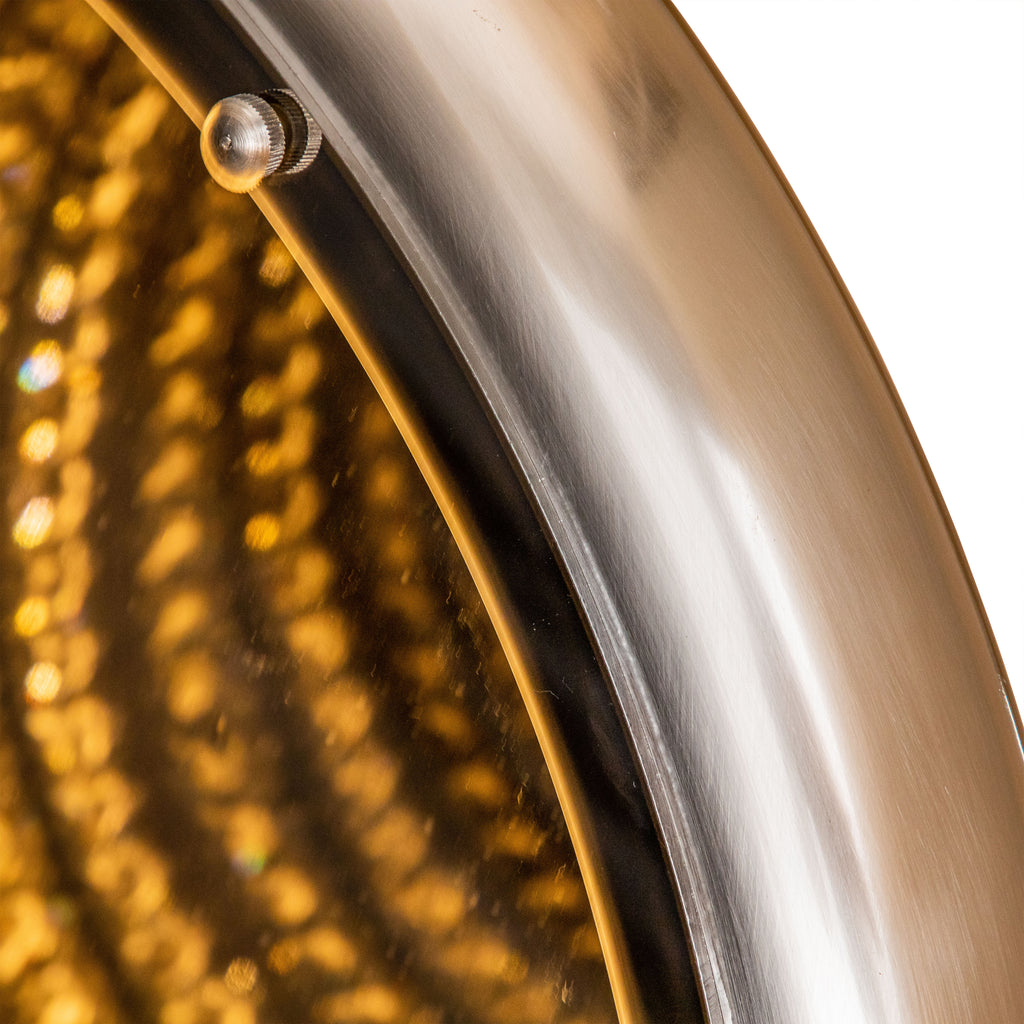 Close-up of the mirror's rounded outer rim and dark inner border beside the golden illuminated pattern.