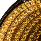 Detail of the illuminated mirror face, with repeated rows of bright golden faceted shapes.