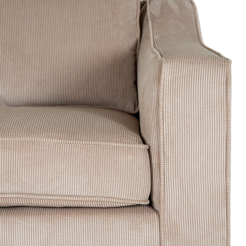 Close view of the cream ribbed seat and back cushions beside a shaped arm with piping around its front border.