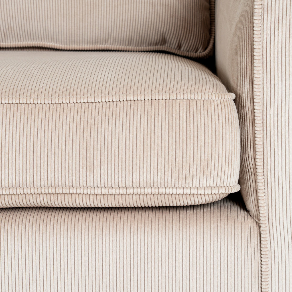 Close-up of the cream seat cushion beside the sofa arm, showing narrow ribs and raised edging.