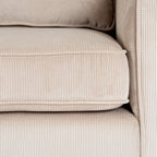 Close-up of the cream seat cushion beside the sofa arm, showing narrow ribs and raised edging.