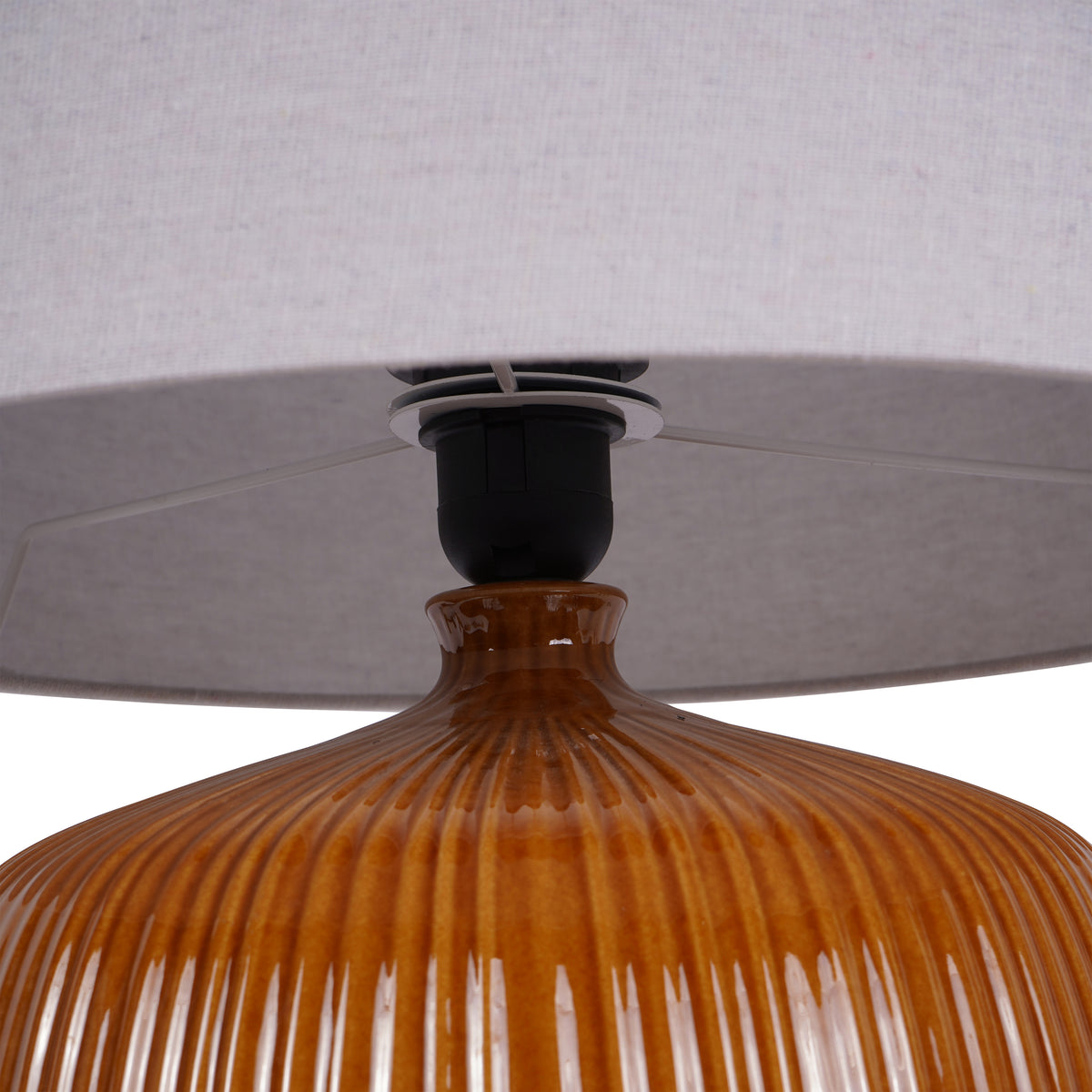 Close-up beneath the shade showing the black lampholder, metal support disc and narrow neck above the ribbed ochre shoulders.
