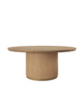 Round wooden dining table with a broad top, vertically ribbed drum pedestal and gold-coloured band at the base, on a white background.