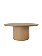 Round wooden dining table with a broad top, vertically ribbed drum pedestal and gold-coloured band at the base, on a white background.