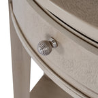 Detail of the round ribbed silver-coloured knob on the pale grey-beige drawer front, with fine darker surface markings visible around it.