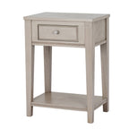 Front three-quarter view of the pale grey-beige side table, showing its framed drawer, ribbed silver-coloured knob and open lower shelf.