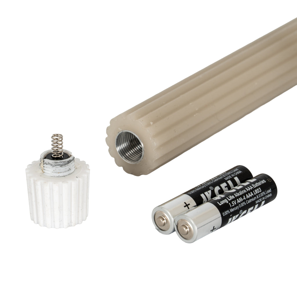 Close-up of a ribbed candle's threaded open lower end beside a removed white screw fitting with a spring and two loose AAA-labelled batteries.