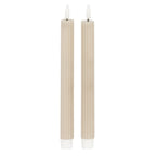 Two slender pale beige-taupe ribbed candles with white flame-shaped tips and white lower fittings against a white background.