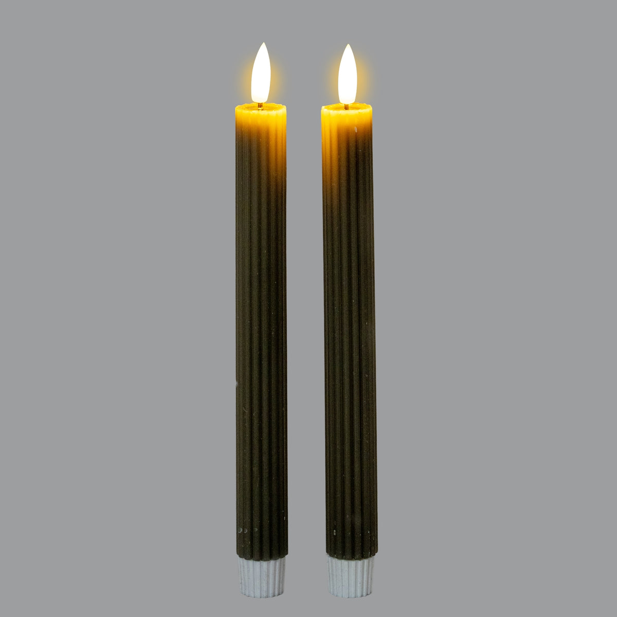Two ribbed candles shown illuminated against a grey background, with bright white flame-shaped tips, yellow light around the tops and bodies appearing very dark.