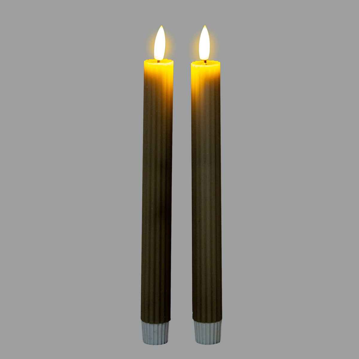 Two ribbed LED candles shown with bright white flame-shaped tops and a yellow glow around their upper edges; the bodies appear dark green against grey.