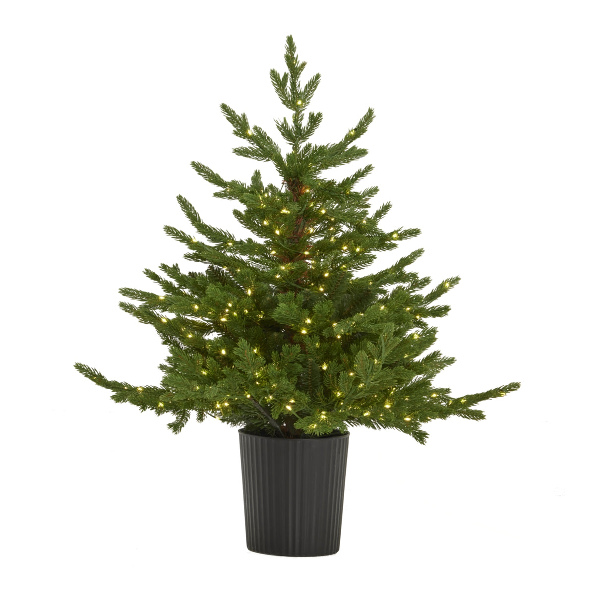 Green artificial fir-shaped Christmas tree shown with lights glowing among spreading branches, in a tapered black ribbed pot.