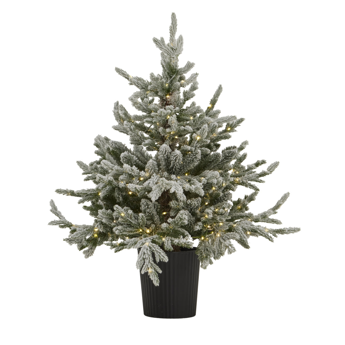 Snow-coated artificial Christmas tree in a tapered black ribbed pot, shown with small yellow lights glowing among the green branches.