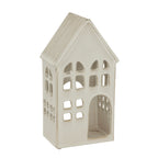 Angled view of the cream-white house candle holder showing its ribbed pitched roof, window openings along the side and hollow interior through the doorway.