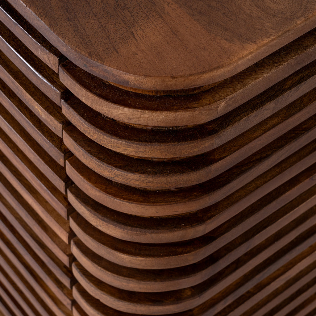 Close-up of the sideboard's rounded top corner and horizontal brown ridges wrapping around the side, with dark recesses between them.