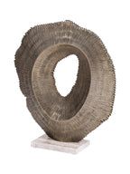 Angled view showing the curved ridged face and projecting inner rim of the antique gold sculpture on its marble base.