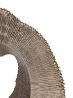 Close-up of deep radiating ridges and the rippled outer edge of the antique gold sculpture.