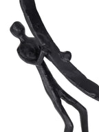 Close-up of one figure gripping the ring, showing the textured black surface and elongated body.