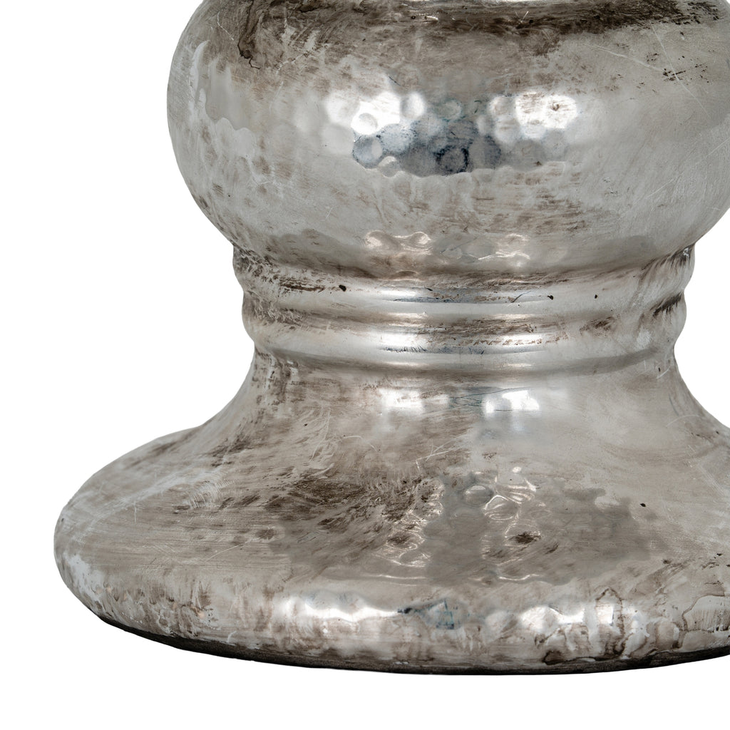 Detail of the candle holder's hammered-effect rounded body, lower bands and flared foot with dark distressed markings.