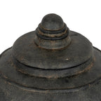 Close-up of the stepped lid and rounded finial, with concentric rings, brown mottling and irregular markings on the dark surface.