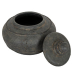 Charcoal-black pot viewed from above with its lid leaning beside it, revealing the circular opening and dark interior.