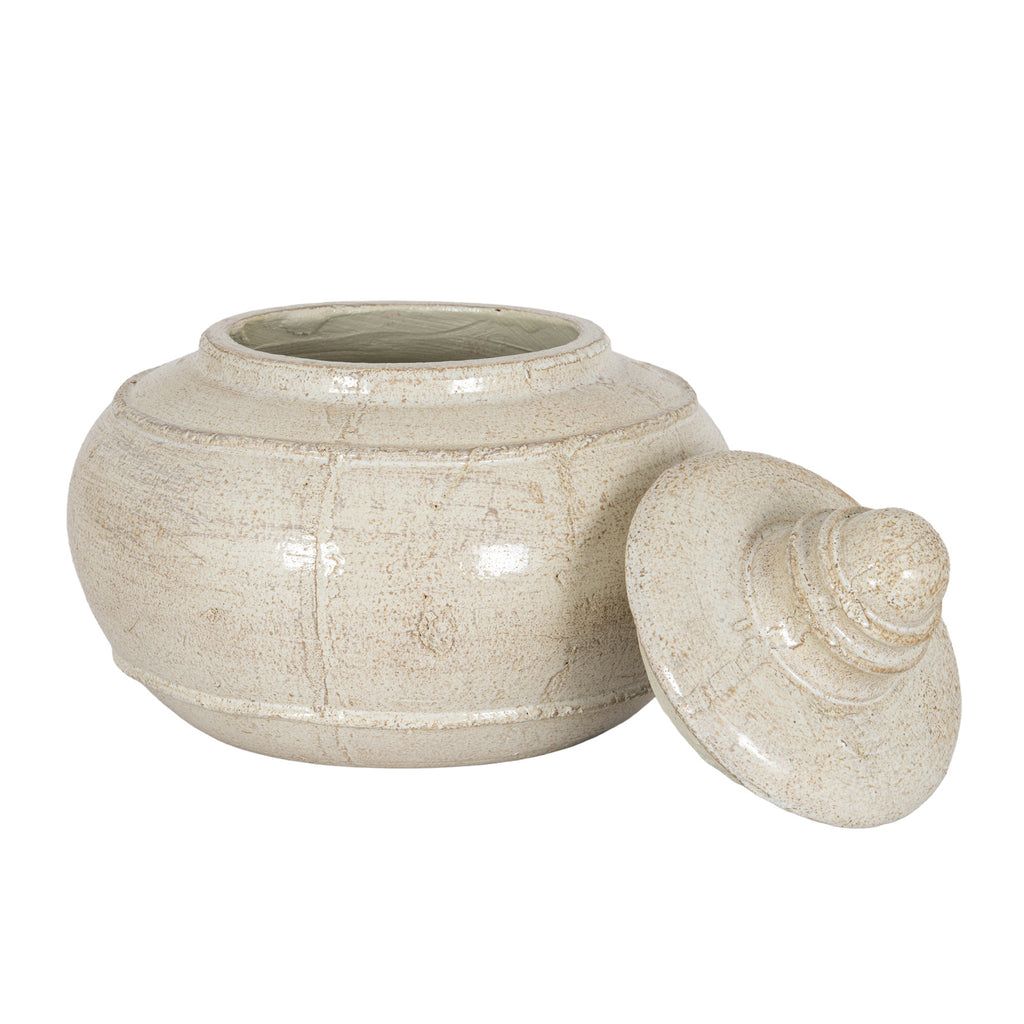 Open cream decorative pot viewed from the front with its lid resting at the right, showing the shoulder band, lower band and low foot ring.