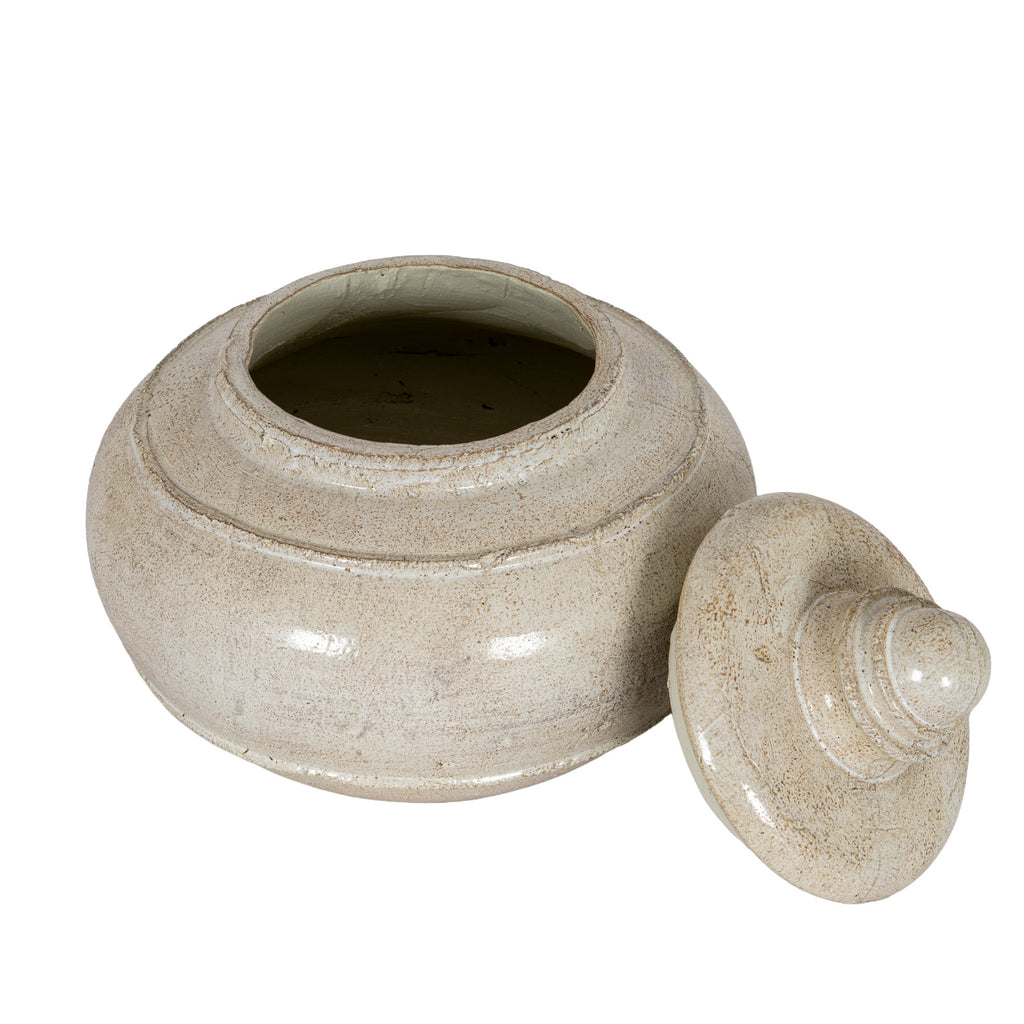 Elevated view of the open cream pot with its lid resting to the right, showing the circular opening and shaded interior.