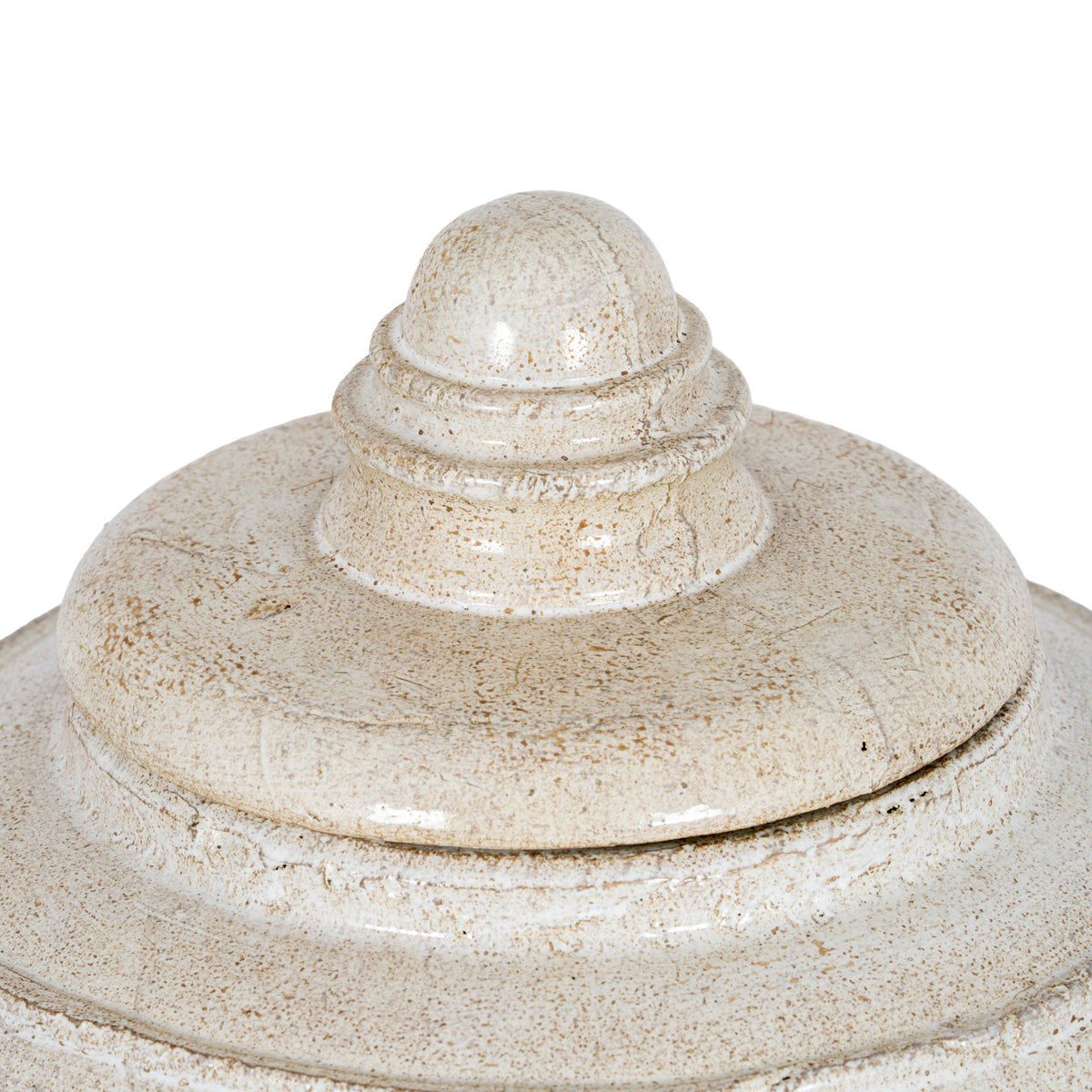 Close-up of the lid's rounded finial and concentric rings, with beige-brown speckling and irregular markings across the glossy cream surface.