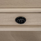 Close-up of a black ring pull centred on a pale grained drawer front with a raised rectangular border.