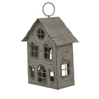 Angled view of the weathered house candle holder showing the ridged roof, front façade and pierced side window.